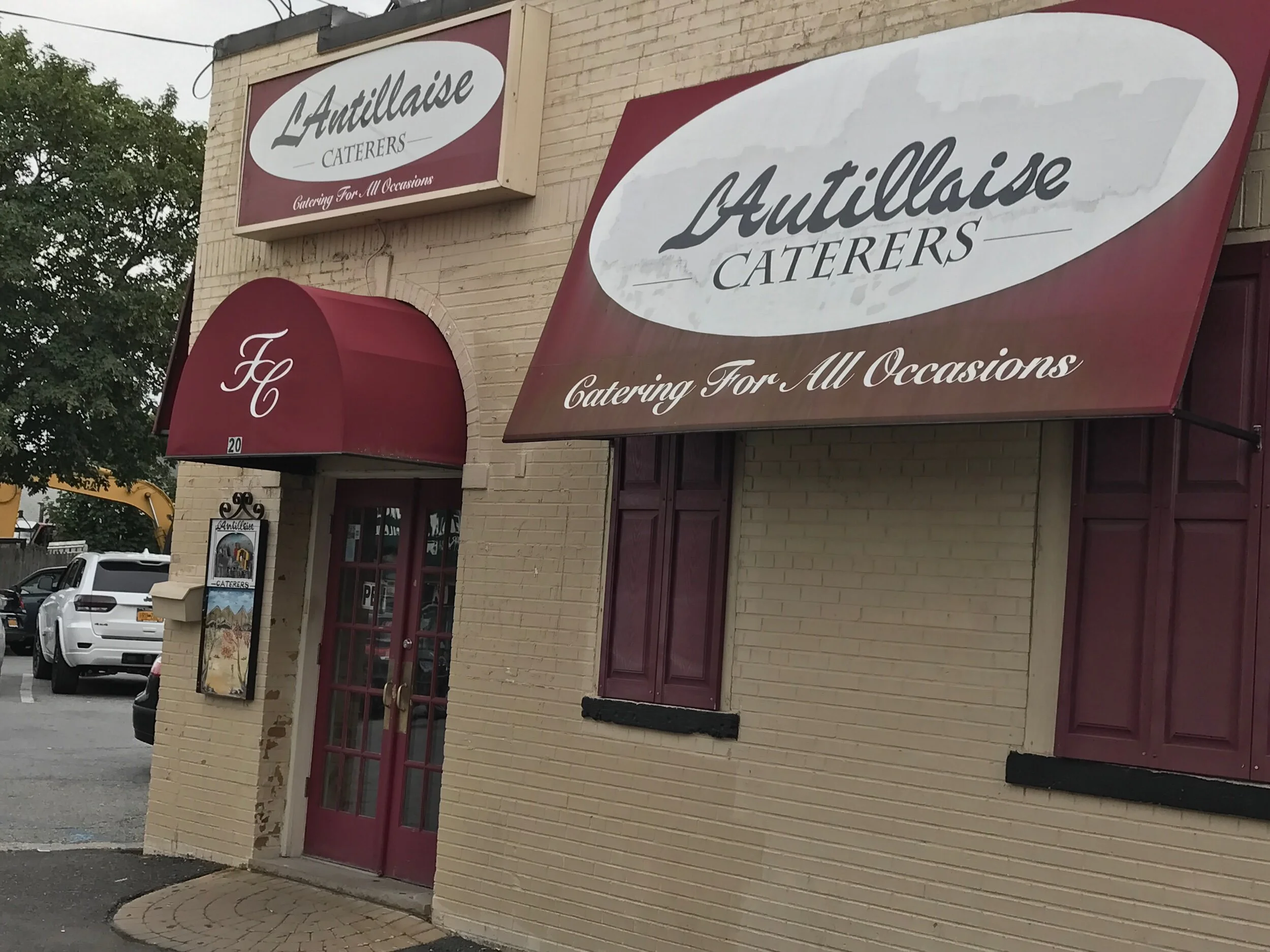 Exterior of L'Antillaise Caterers with its name on the awning at 20 New Hyde Park Road